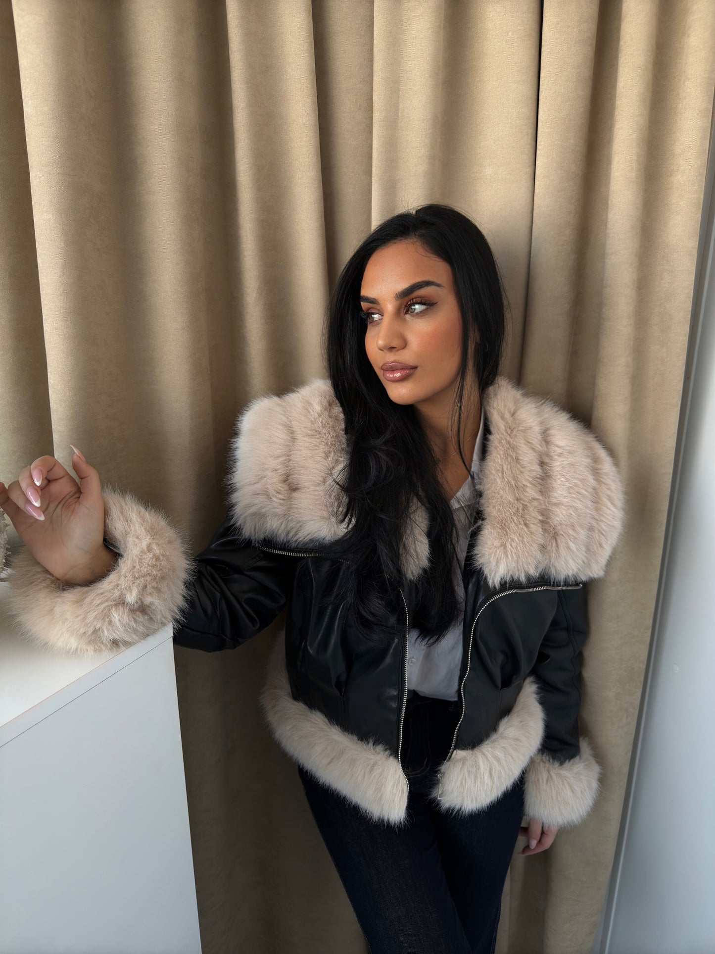 Black faux leather jacket finished with soft beige faux fur trim on the collar, sleeves, and hem.