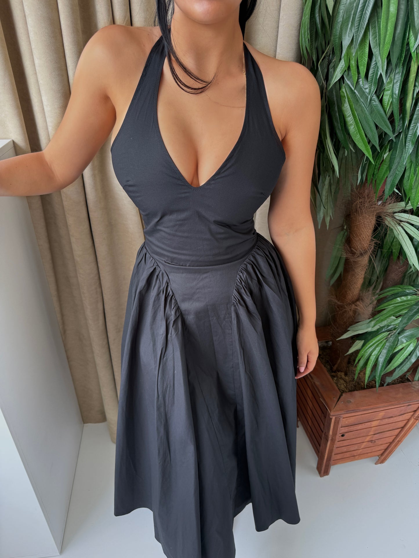 Elegant black midi dress featuring a flattering V-neckline, halter tie-back, and a voluminous wide skirt.