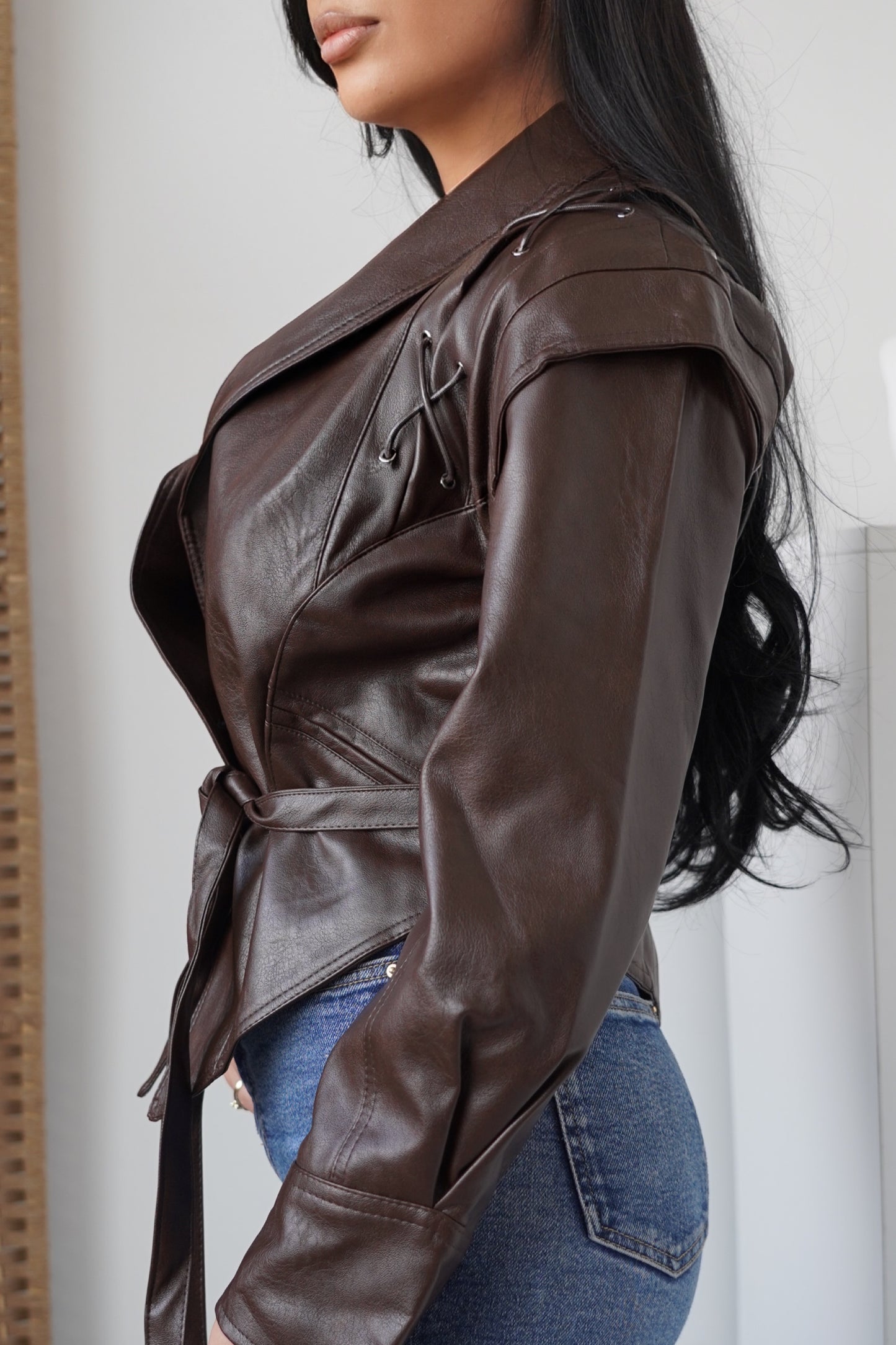 Elegant faux leather jacket in dark brown, featuring a modern cut and a waist belt for a flattering silhouette.
