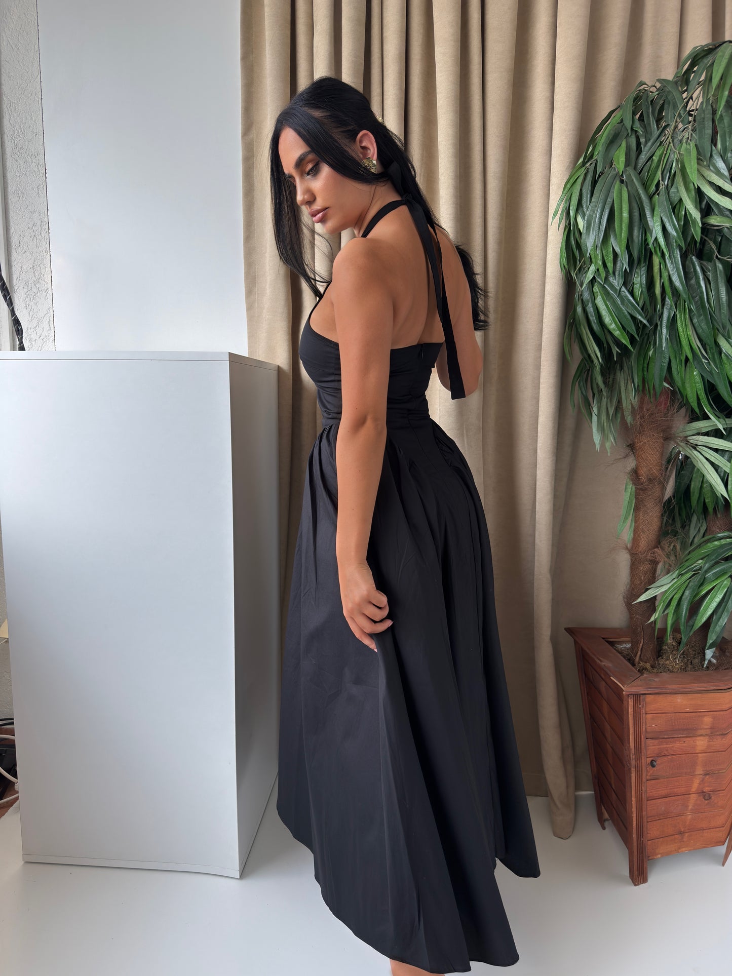 Elegant black midi dress featuring a flattering V-neckline, halter tie-back, and a voluminous wide skirt.