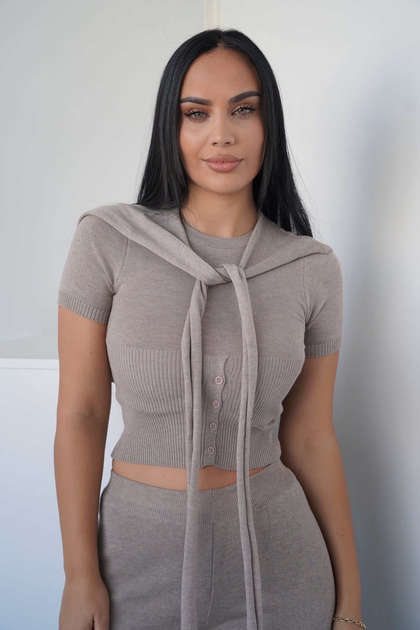 This modern and stylish two-piece set features a short-sleeve crop top with a tied scarf detail at the neckline, paired with high-waisted wide-leg pants.