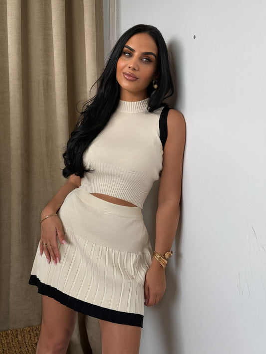 Elegant two-piece set consisting of a sleeveless top and a pleated mini skirt.