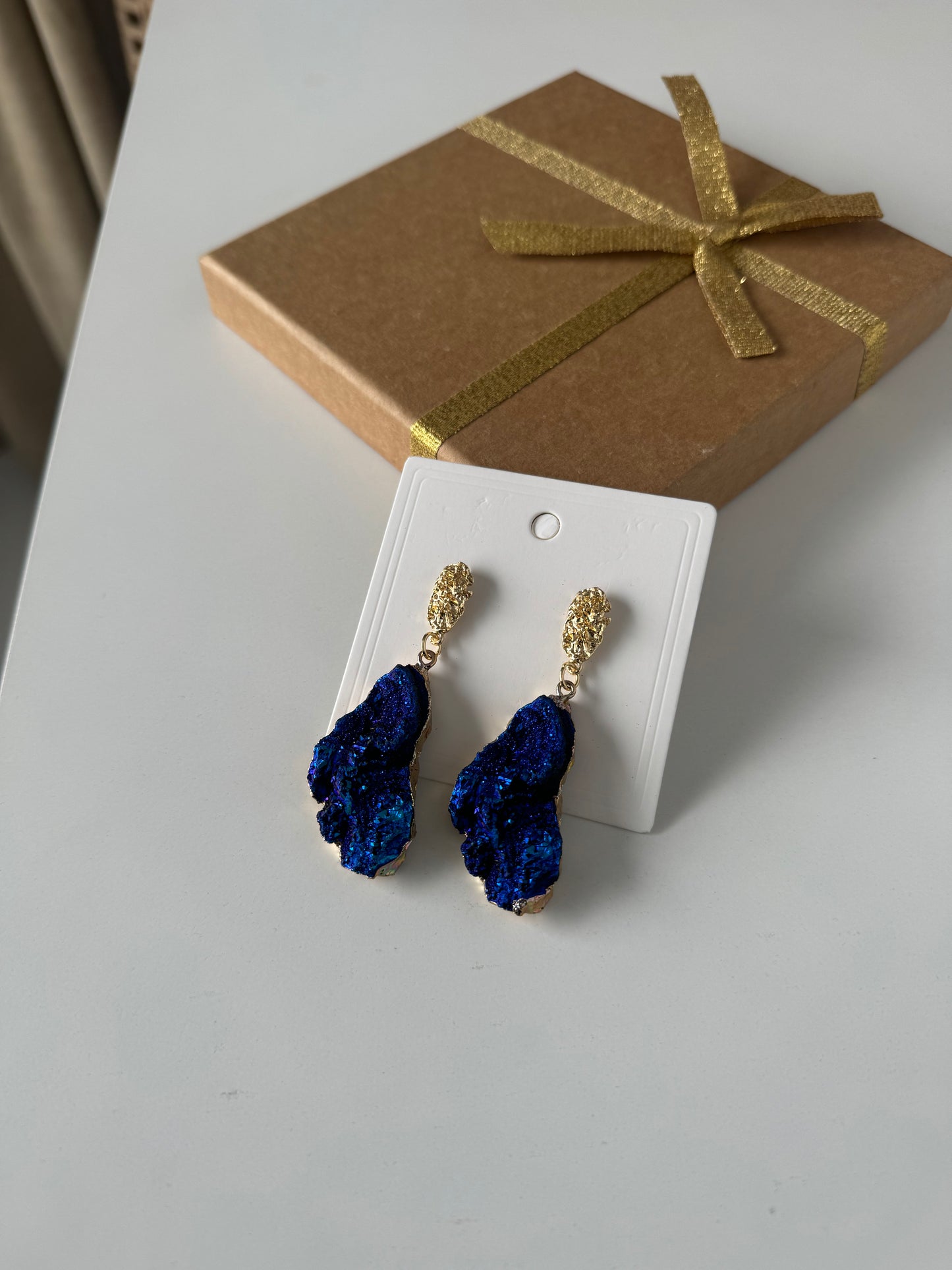 Bold and elegant, these earrings feature richly textured stones in a metallic deep blue tone