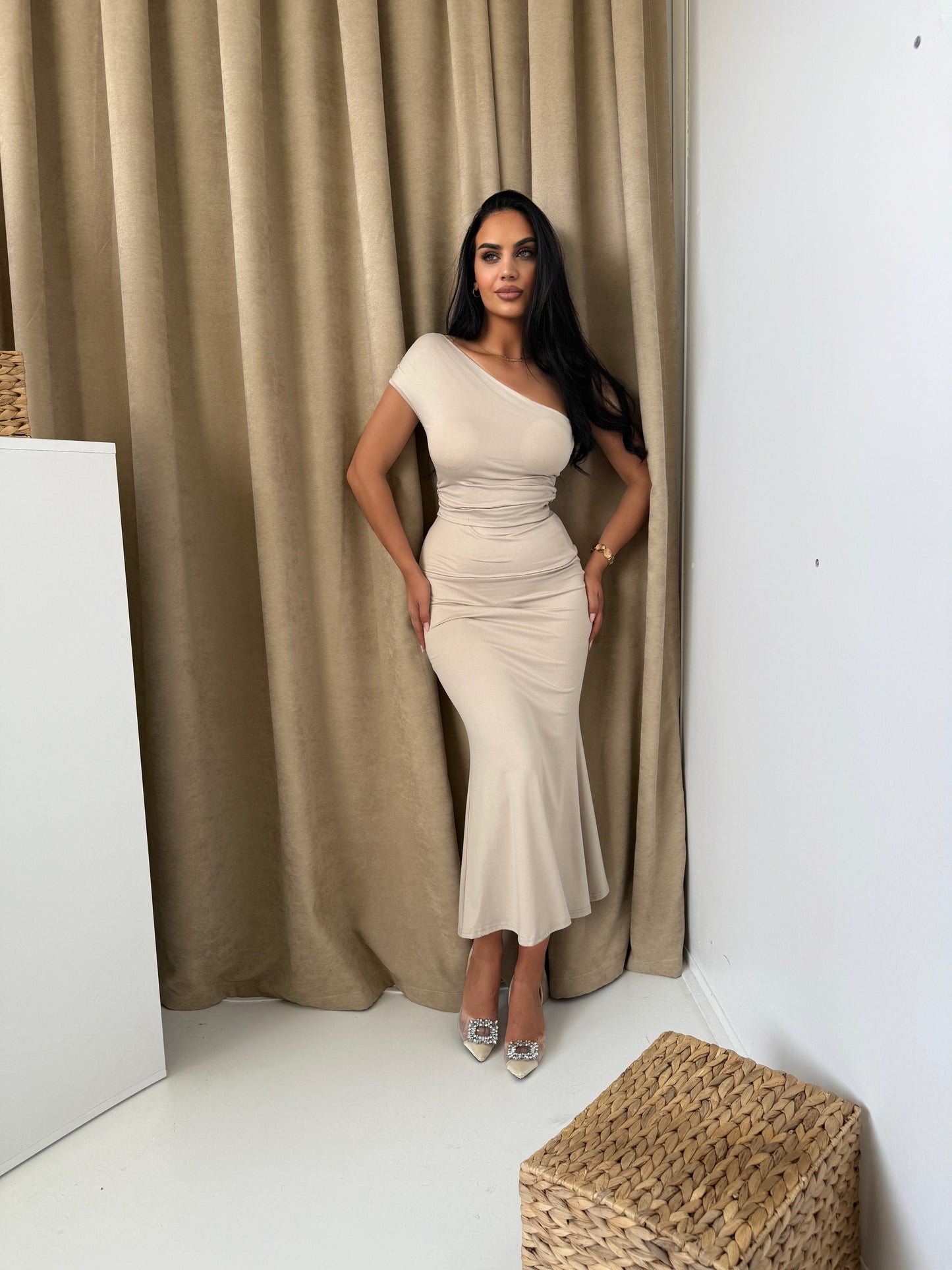 Beige two-piece set with a sleek one-shoulder top and a fitted mid-calf skirt